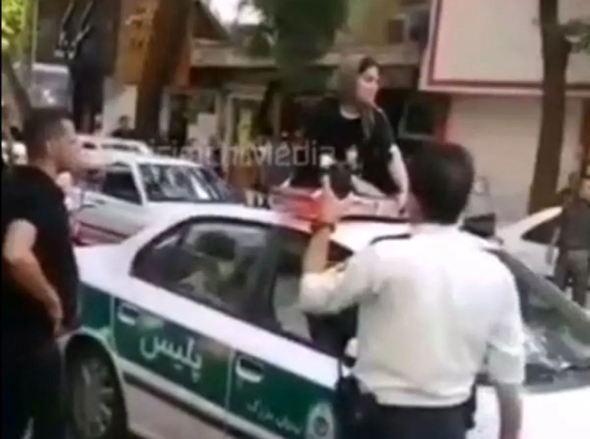 (ویدئو) یک زن روی سقف ماشین پلیس:‌ شوهرم را آزاد کنید!