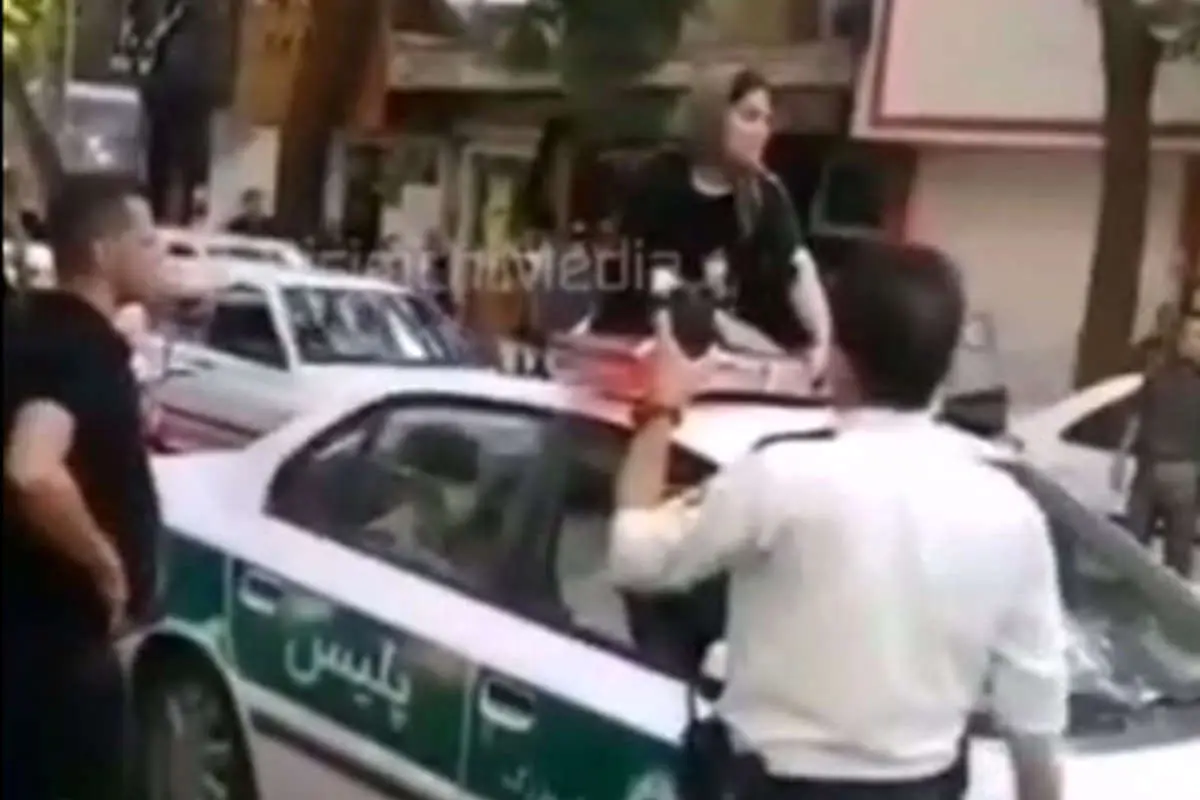 (ویدئو) یک زن روی سقف ماشین پلیس: شوهرم را آزاد کنید!