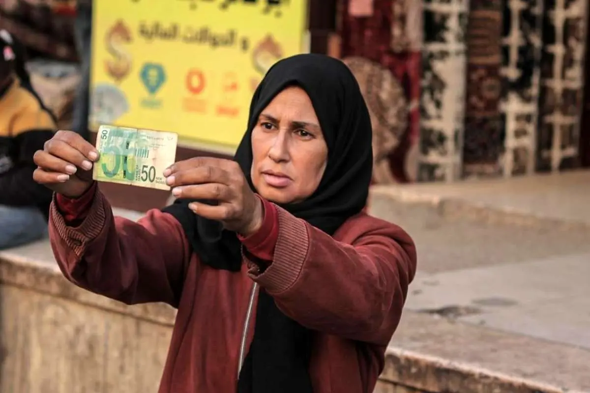 تصاویر؛ زن فلسطینی با ترمیم اسکناس‌های پاره امرار معاش می‌کند